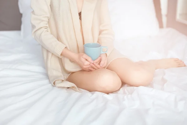Jovem mulher bebendo seu café enquanto sentada na cama — Fotografia de Stock