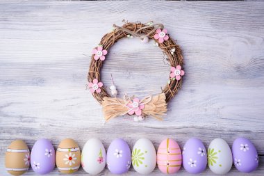 Painted colorful Easter eggs and nest on grey wooden background