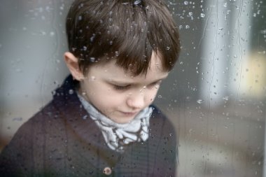 7 yaşındaki çocuğun pencerenin kenarında duran Sad depresif