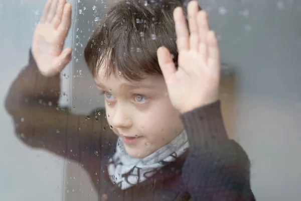 Jovem 7 anos de idade menino de pé ao lado da janela — Fotografia de Stock