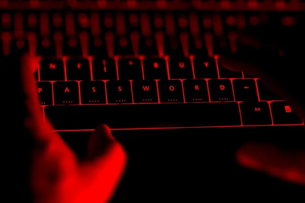 Hacker tippen nachts auf der beleuchteten Tastatur. — Stockfoto