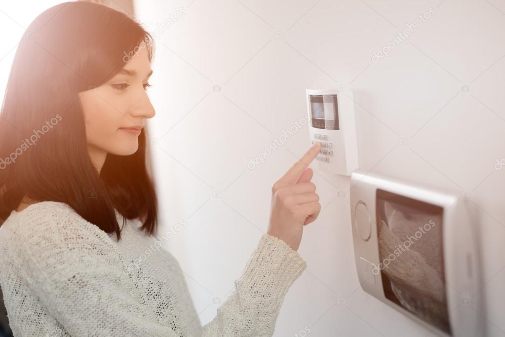 woman entering code on keypad of home security alarm