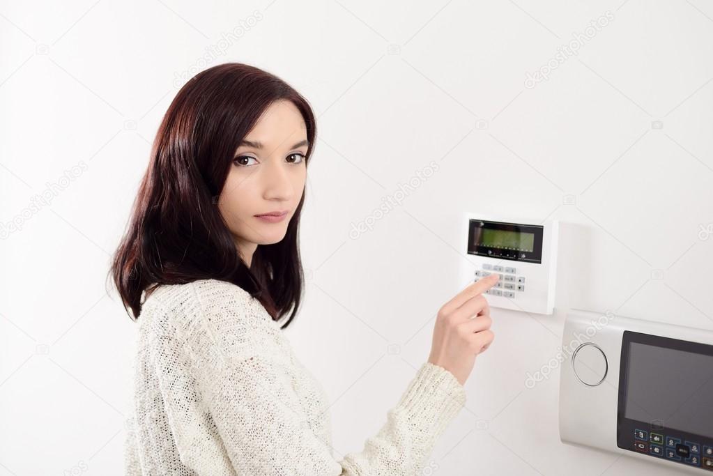 woman entering code on keypad of home security alarm