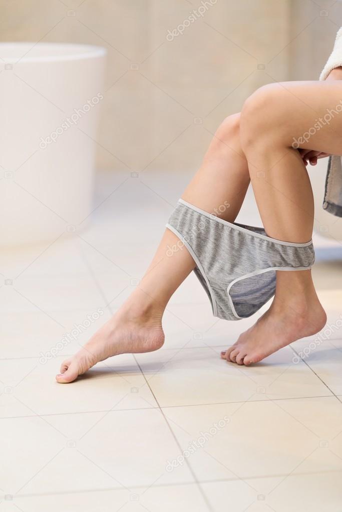 Side view of brunette woman sitting on toilet 
