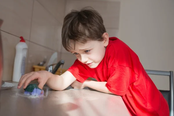 7 yıl yaşlı erkek çocuk mutfak dolaplarında temizler. — Stok fotoğraf
