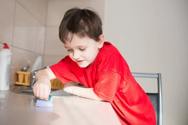 7 year old boy cleans cabinets in the kitchen — Stock Photo, Image