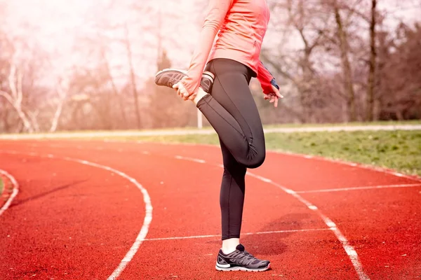 Woman stretching on a running track. — Stock Photo, Image
