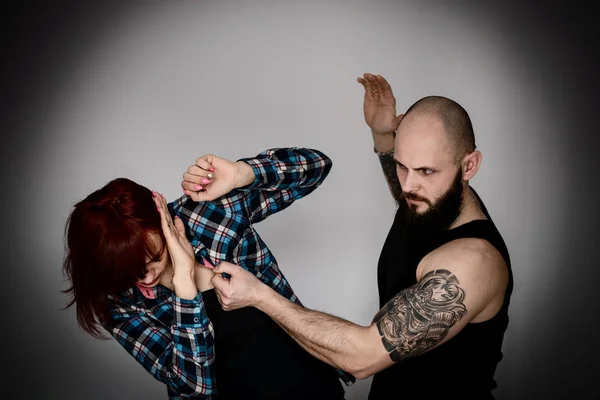 Muscular bearded man beating his redhead wife. — Stock Photo, Image