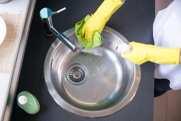 Kädet keltaisissa kumihanskoissa pesemässä pesuallasta — kuvapankkivalokuva