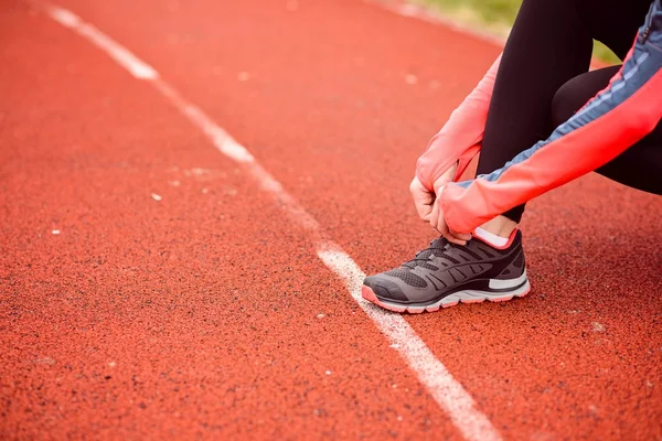 Kadın atlet ayakkabısını bağlıyor