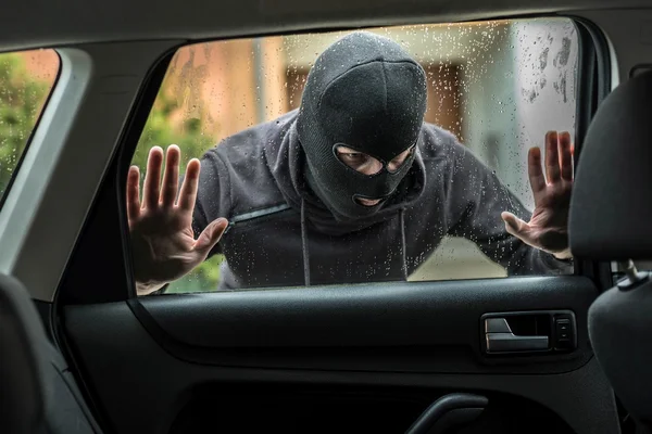 Car thief looking through car window — Stock Photo, Image