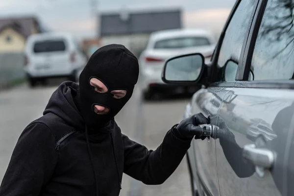 Autodieb zieht am Griff eines Autos. — Stockfoto