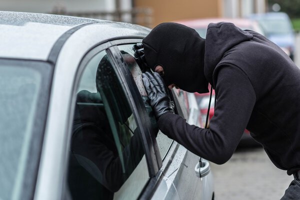 Автоугонщик смотрит в окно машины
 