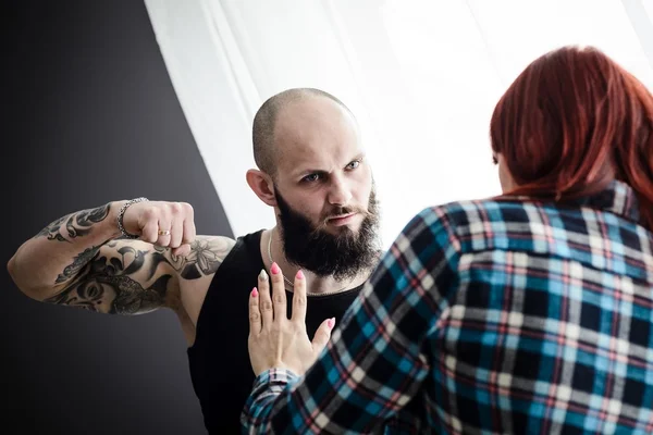 Tattooed muscular man beating his redheaded wife. — Stock Photo, Image