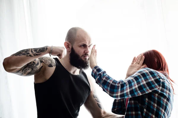 Getatoeëerde gespierde man mishandeling van zijn roodharige vrouw. — Stockfoto