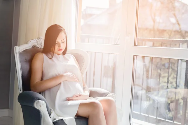 Young pregnant mom sitting on the armchair — Stock Photo, Image