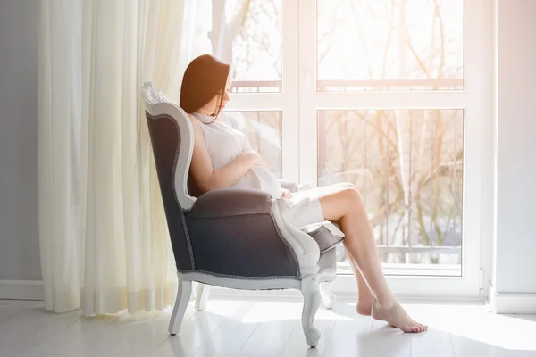 Young pregnant mom sitting on the armchair — Stock Photo, Image