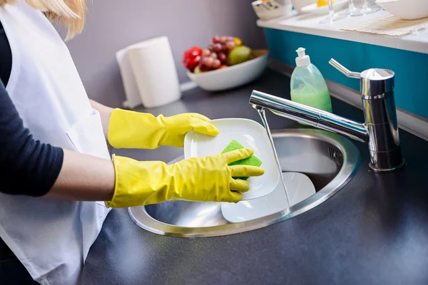 Žena, mytí nádobí v kuchyni s houbou. — Stock fotografie