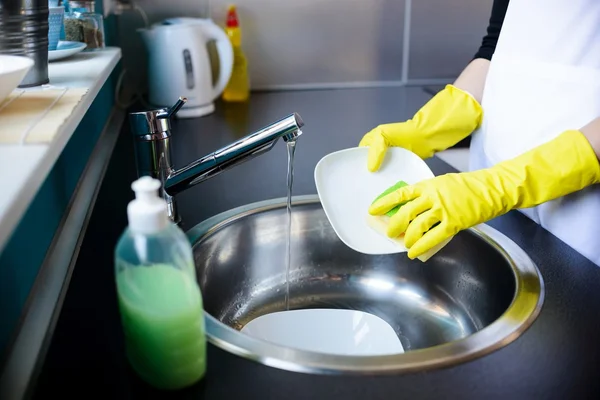 Mujer lavando platos en la cocina con esponja . — Foto de Stock