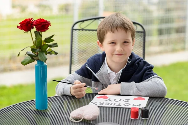 Menino menino pintando cartão de saudação para sua mãe — Fotografia de Stock