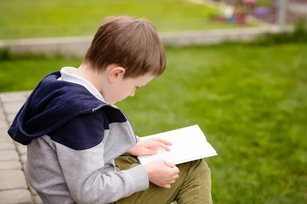 7 év régi fiú Olvasson egy könyvet a teraszon — Stock Fotó