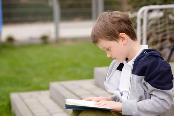 7-årig pojke läser en bok på terrassen — Stockfoto