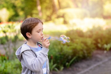 Küçük çocuk parkta sabun köpüğü üfleme