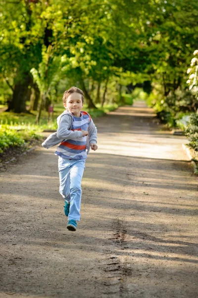 Malý chlapec běží v parku. — Stock fotografie