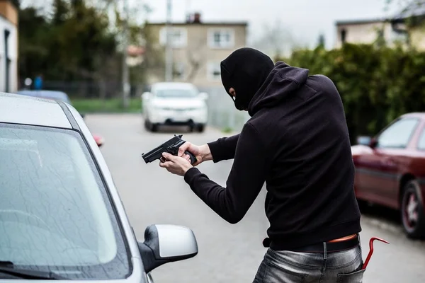 Car thief pointing a gun at the driver — Stock Photo, Image