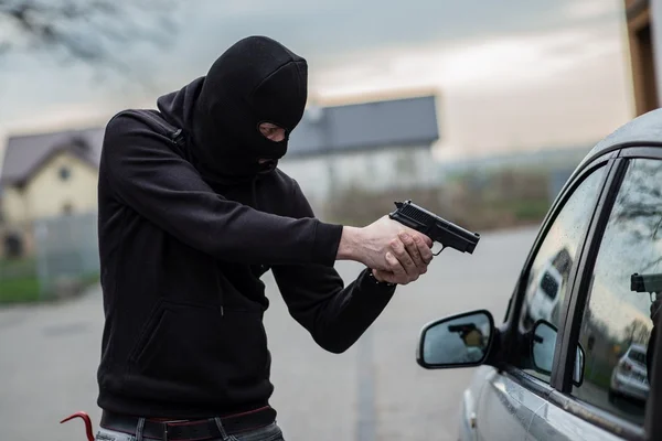 Car thief pointing a gun at the driver — Stock Photo, Image