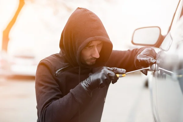 Ladrão de carros tentando invadir um carro com uma chave de fenda . — Fotografia de Stock