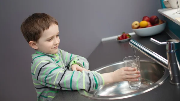 Chico vertiendo agua del grifo en un vaso — Foto de Stock