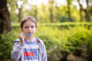 Küçük çocuk sabun köpüğü üflüyor.