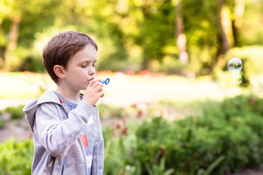 Küçük çocuk sabun köpüğü üflüyor.