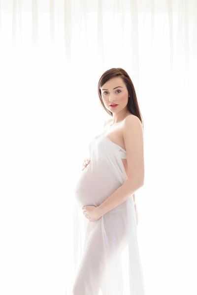 Brunette femme enceinte debout sur fond blanc — Photo