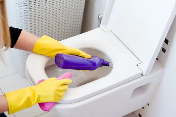 Donna in guanti di gomma gialla pulizia toilette — Foto Stock