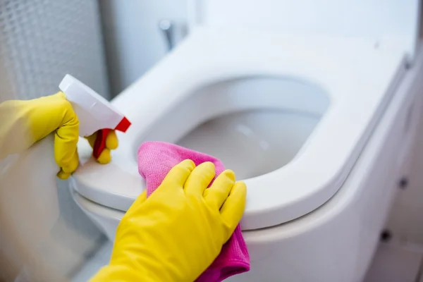 Жінка в жовтих гумових рукавичках прибирає туалет — стокове фото