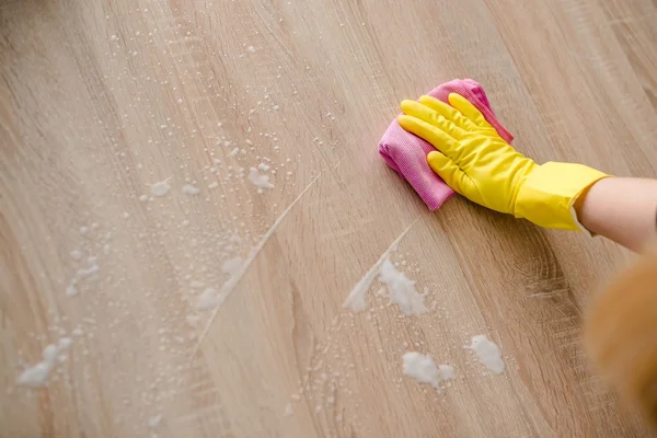 Žena v žluté gumové rukavice čištění tabulka — Stock fotografie