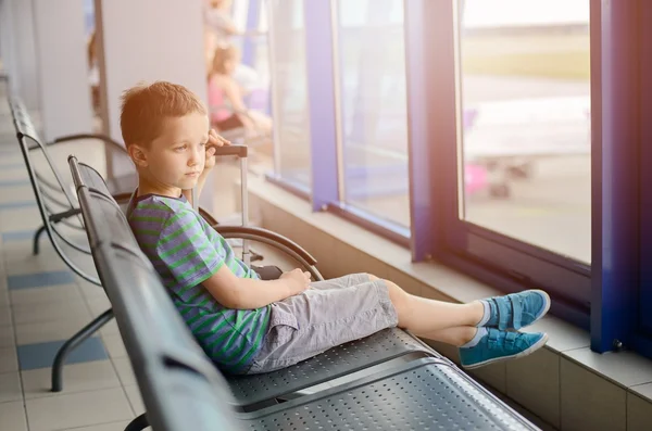 Junge sitzt mit seinem Gepäck am Flughafen — Stockfoto