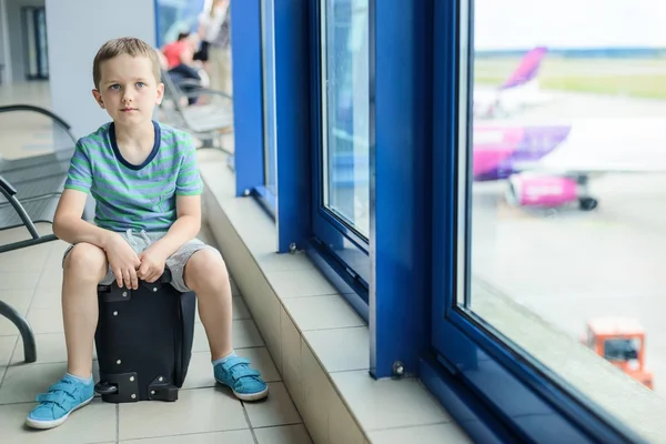 Kind sitzt am Flughafen am Gepäckstück — Stockfoto