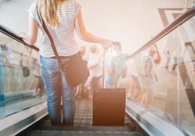 Bavulunu yürüyen merdiven üzerinde kadınla