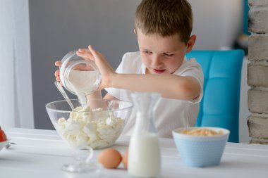 Bir kase süzme peynir için şeker ekleyerek çocuk.