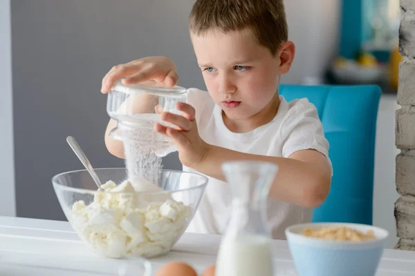 Bambino che aggiunge zucchero ai fiocchi di latte in una ciotola . — Foto Stock