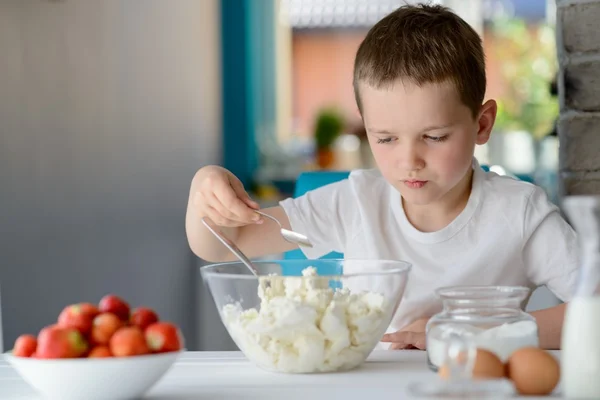 Niño añadiendo azúcar al requesón en un tazón . — Foto de Stock