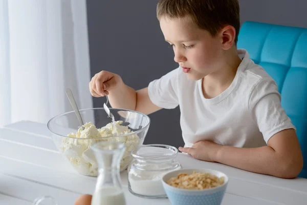 Niño añadiendo azúcar al requesón en un tazón . — Foto de Stock