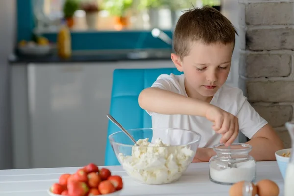 Bambino che aggiunge zucchero ai fiocchi di latte in una ciotola . — Foto Stock