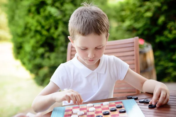 Pequeño niño jugando damas juego de mesa — Foto de Stock