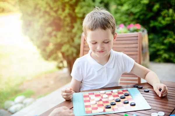 Kleine jongen spelen van dammen bordspel — Stockfoto