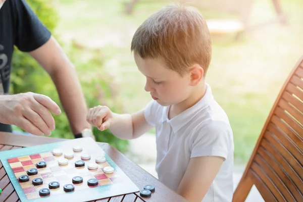 Liten pojke spelar pjäser brädspel — Stockfoto