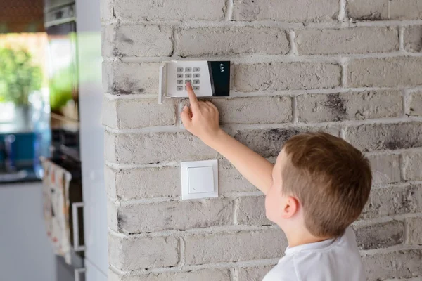 Kleiner Junge drückt einen Knopf auf der Alarmtastatur — Stockfoto